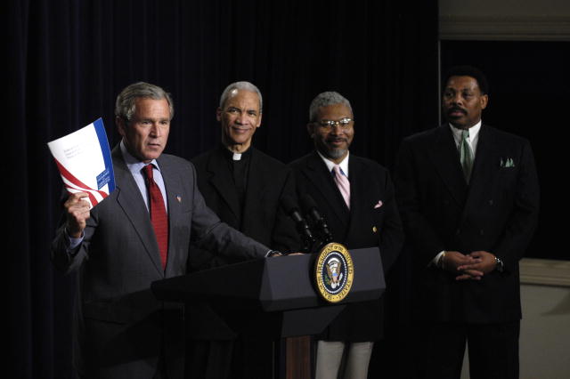 President Bush at a podium with three African American urban leaders. 