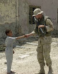 An Iraqi boy greets Steelworker 2nd Class Christopher Grau assigned to the Naval Mobile Construction Battalion Seven (NMCB-7) security team, upon his arrival at a school in Nasiriyah
