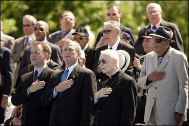 President George W. Bush sings the National Anthem with World War II veterans during the dedication of at the National World War II memorial on the Mall in Washington, DC on May 30, 2004. White House photo by Paul Morse.