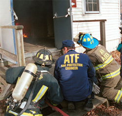 Three ATF men looking into a burning building.