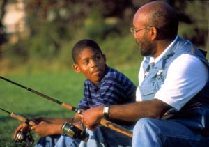 Foto de un padre y un hijo afroamericanos pescando y conversando