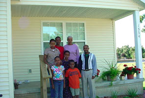 Picture of Misk and Heydar Sharif and five of their six children on the front porch of their new home