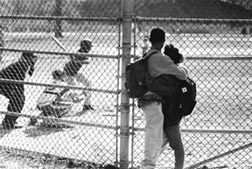 Photo of teenage couple watching a youth baseball game