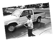 Photo of boy with a hose washing a pickup truck