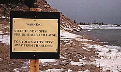 warning sign on beach about collapsing slopes