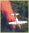 Photo of an air tanker dropping fire retardant on a fire.