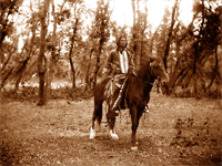 Titled, 'Ozuye Wicasa,' - A Warrior Man.  The glass plates for this majestic image were exposed near the backwaters of the river bottoms near Yankton or Greenwood, S.D., between 1886 and 1900.  The rider's dress includes clothes worn in traditional Native American dance occasions: moccasins, a shirt appropriate for a pow-wow, or wacipi, a breastplate, and personal medicine indicating a commitment to the traditional Lakota Sacred Pipe religion.  Notice the traditional dancer's belt draped across the saddle horn.  This man most likely paused for a picture before riding his horse to a Native American dance hall.  -- select to view larger image.