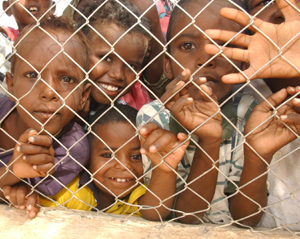 Djiboutian children peer through the fence at military personnel from the US France and Germany as well as a Djiboutian doctor during the Medical Civil Action Program in As Eyla, July 19. A key element of the Combined Joint Task Force ? Horn of Africa mission lies in making a positive difference in the lives of the people in the region and their environment. Photo by: Sgt. Bradly Shaver