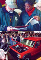 A man and woman looking at a document; a group of people at an auto auction looking at a red SUV with its hood up.