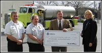 FEMA Region IX Regional Director Jeff Griffin presents the Reno Fire Department with a check to go toward a firefighting vehicle like the one in the background. FEMA News John Shea