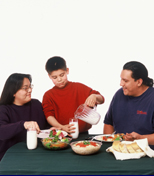 Native American family sitting at table enjoying a meal prepared with USDA Commodities.