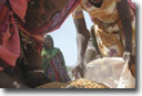 Women putting dried corn into a U.S. food aid bag