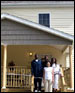 [Photo: Shelly Hill family standing in the front porch of their new home]