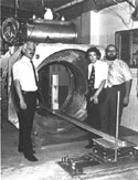 Drs. Raymond Damadian, Lawrence Minkoff, and Michael Goldsmith (left to right) and the completed Indomitable (the worlds first magnetic resonance scanner) that performed the first scan of a live human being. NSF-supported fundamental research led to the development of magnetic resonance imaging (MRI) technology.  <I>[See related images: Sagittal MRI Image of Brain and First Human MRI Scan.]</I><BR>
<BR>
<U><B>More about this Image</B></U><BR>
Fundamental research, supported by the NSF, led to the development of magnetic resonance imaging (MRI) technology. MRI is widely used in hospitals for purposes like detecting tumors and internal tissue damage in patients, and investigating differences in brain tissue.<BR>
<BR>
MRI technology works like this. An MRI imager surrounds a patient with magnets. The magnetic field created by the magnets causes atomic nuclei in the patients body to line up parallel to the field. A coil in the imager jars the nuclei with radio waves. They resonate, producing a faint radio signal that a computer amplifies and translates into an image. Unlike X-rays or CAT scans, MRI lets doctors distinguish blood vessels from malignant tissue.  Thumbnail