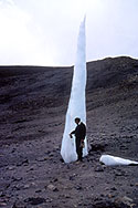 One of the last remnants of Mt. Kilimanjaro's Eastern ice field is a six-meter spire that was much larger when seen on earlier expeditions by researchers studying past climate conditions. It is expected to vanish in a few years due to global warming.  <I><B>[Image is one of several related images; see also: Twelve-Meter Spire, Outer Margin of Furtwangler Ice Field, Layer of Dust Inside Ice Core, and Area of Ice on Kilimanjaro.]</B></I><BR>
<BR>
<font color=#DC143C><B><U>Important:</U>  Use of this image is restricted. Please see Restrictions (below) for complete information.</font></B><BR>
<BR>
<U><B>More about this Image</B></U><BR>
Ice cores contain an abundance of information about the earths climate in the past. They are the most effective natural recorder of climate change, more so than tree rings or sediment layers. Ice cores taken from certain undisturbed locations can contain an uninterrupted, detailed climate record extending back hundreds of thousands of years. This record can include temperature, precipitation, chemistry and gas composition of the lower atmosphere, volcanic eruptions, solar variability, sea-surface productivity, and a variety of other climate indicators.<BR>
<BR>
In 2000, National Science Foundation-grantee Lonnie Thompson, a geological science professor from Ohio State University (OSU), led an expedition to drill six ice cores from the ice fields on Mt. Kilimanjaro. While camping for a month at their drill site located above 19,300 feet, Thompson and his team collected 215 meters (705 feet) of frozen ice core, which they brought back to OSUs Byrd Polar Research Center.<BR>
<BR>
Analysis of the core suggests dramatic changes in the climate and temperature on and around Mt. Kilimanjaro since the ice fields were formed approximately 11,700 years ago. For example, around 9,500 years ago, the landscape was far wetter and different. Today, Lake Chad is the fourth largest body of water on the African continent, measuring about 17,000 square kilometers. But 9,500 years ago, it covered some 350,000 square kilometersan area larger than the Caspian Sea!<BR>
<BR>
Analysis of the ice cores also indicates evidence of three catastrophic droughts that took place:
<ul><li>A 500-year-period beginning around 8,300 years ago, when methane levels in the ice dropped dramatically. Thompson believes this represents a time when Africas lakes were drying up.</ul></li>
<ul><li>An abrupt depletion in oxygen-18 isotopes that researchers believe signals a second drought event occurring around 5,200 years ago.</ul></li>
<ul><li>A visible dust layer in the ice cores dating back to about 4,000 years ago. Thompson believes this marks a severe 300-year drought that struck the region. Historical records show that a massive drought rocked the Egyptian empire at the time. According to Thompson, up until this time, people had been able to survive in areas that are now just barren Sahara Desert.</ul></li>
Thompson believes that whatever happened to cause these dramatic climate changes in the past, could certainly occur again. He has already predicted that Kilimanjaros ice fields will vanish within 15 years. His team found that the summit of the ice fields has lowered by at least 17 meters (nearly 56 feet) since 1962, an average shrinkage of about a half-meter in height each year. In addition, the margin of the ice field has retreated as much as one meter since 2000a meters worth of ice lost from a wall 50 meters (164 feet) high!  Thumbnail
