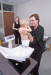 Photo: Nutritionist Pat Wiggins weighs a 1-year-old boy while his mother watches. Link to photo information