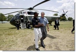 President George W. Bush walks with YMCA volunteer Andrew Simpson after arriving on Marine One in Dallas, Texas, Friday, July 18, 2003. White House photo by Paul Morse.