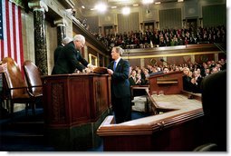President George W. Bush hands Vice President Dick Cheney and Speaker of the House Dennis Hastert (not pictured) a copy of his State of the Union Address upon his arrival to the House Chamber at the U.S. Capitol Tuesday, Jan. 28, 2003.  White House photo by Eric Draper