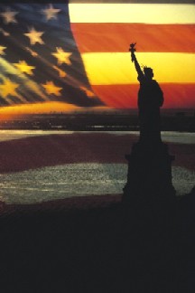 Statue of Liberty silhouetted against a sunlit flag