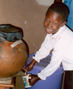 Young boy fills mug with clean water from a Safe Water System filtered water pot. Photo courtesy Valerie Garrett.