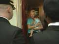 Photo of woman holding a baby in a doorway with CACO personnel greeting her.