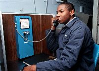 A crew member takes advantage of one of the commercial phone lines available aboard ship while deployed at sea.
