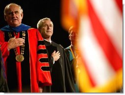 President George W. Bush stands on stage with LSU President William Jenkins during the singing of the National Anthem before delivering remarks at the Louisiana State University Commencement in Baton Rouge, La., Friday, May 21, 2004. White House photo by Eric Draper.