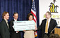 Secretary Chao presenting a facsimile check to (L-R) Regis Winniewicz (employee, Renal Solutions), Martin Olshinsky (Vice President, Community College of Allegheny County), and Dr. Doros Platika (President and CEO of the Pittsburgh Life Sciences Greenhouse).