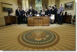 President George W. Bush delivers a Live Radio Address surrounded by Mrs. Bush and families of victims of 911 in the Oval Office, Saturday, Sept. 11, 2004. White House photo by Eric Draper.