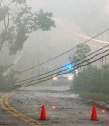 police car guards fallen power lines on storm-damaged road