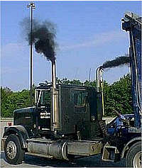 Photo of a semi truck with black smoke spewing from its dual pipes