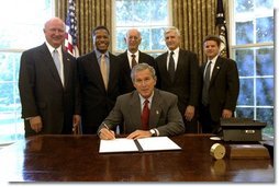 President George W. Bush signs an Executive Order implementing his Volunteers for Prosperity initiative in the Oval Office Thursday, Sept. 25, 2003. Pictured with the President are, from left: Deputy Secretary of Commerce Samuel W. Bodman; Deputy Secretary of Health and Human Services Claude A. Allen; Administrator, Agency for International Development, Andrew Natsios; Under Secretary of State Alan Larson; and Director, USA Freedom Corps, John Bridgeland. White House photo by Tina Hager.
