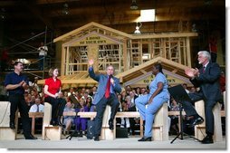 President George W. Bush acknowledges the audience at the conclusion of a conversation on homeownership at the Carpenters Training Center in Phoenix, Ariz., Friday, March 26, 2004. Pictured on stage with the President, from left, are construction foreman Jorge Sotelo, first-time homebuyer Emily McElhaney, first-time hombuyer Monica Sims and Doug McCarron, General President of the United Brotherhood of Carpenters and Joiners of America. White House photo by Eric Draper.