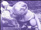 Young boy drinking from water spigot.