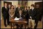 President George W. Bush signs S. 2634, the Garrett Lee Smith Memorial Act, in the Roosevelt Room Thursday, Oct. 21, 2004. The act authorizes the spending of $82 million for youth suicide prevention programs at college campus mental health centers. The legislation is named for Garret Smith, the son of Sen. Gordon Smith, R-Ore., and Sharon Smith, who are standing directly behind the President. Their son committed suicide Sept. 8, 2003. White House photo by Paul Morse.