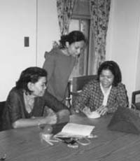 Woman gathered around a table, reviewing documents and materials.