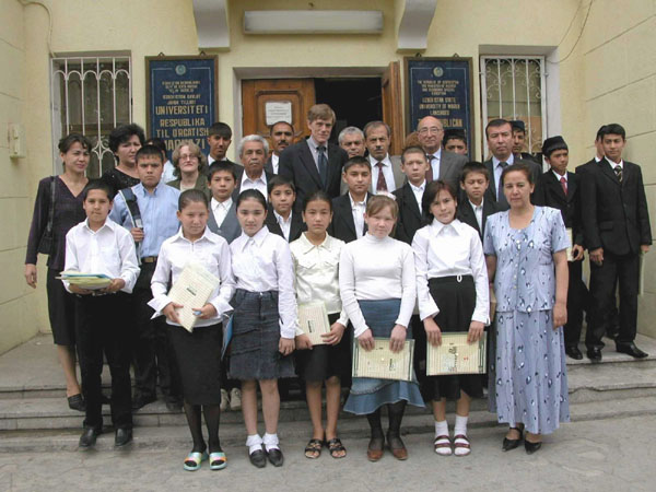 students pose on school steps along with Ambassador Purnell and school officials and teachers