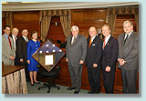 Members of Congress and NSF Director beside flag.