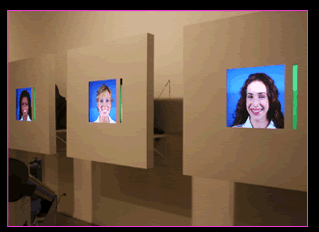 The CHEESE exhibit featuring the faces of smiling women on wall mounted screens.