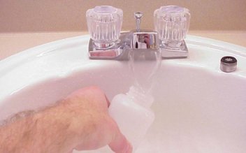 Person taking water sample from bathroom sink
