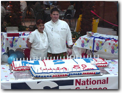 Chefs pose in front of cake;caption is below.